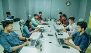 Group of professionals collaborating in a modern office setting on laptops and digital devices. — Photo by Ofspace LLC, Culture on Pexels