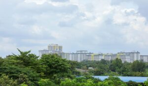 Urban cityscape featuring high-rise residential buildings with lush greenery in the foreground under a cloudy sky. — Photo by Manh Cuong Le on Pexels