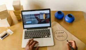 Workspace with laptop, packaging, and handwritten LLC notes, ideal for a small business startup scene. — Photo by RDNE Stock project on Pexels