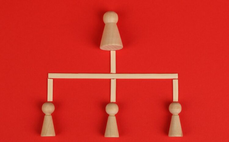 Conceptual depiction of hierarchy using wooden pieces on a vibrant red background. — Photo by Ann H on Pexels